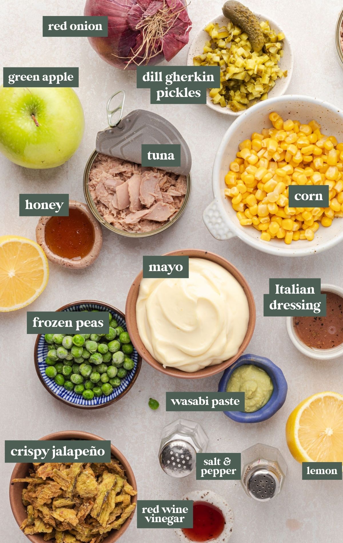 Bowls of ingredients including red onion, gherkin pickles, green apple, tuna, frozen corn, tuna, honey, mayo, frozen peas, crispy jalapeno, red wine vinegar, wasabi paste, salt and peper, lemon, and Italian dressing.