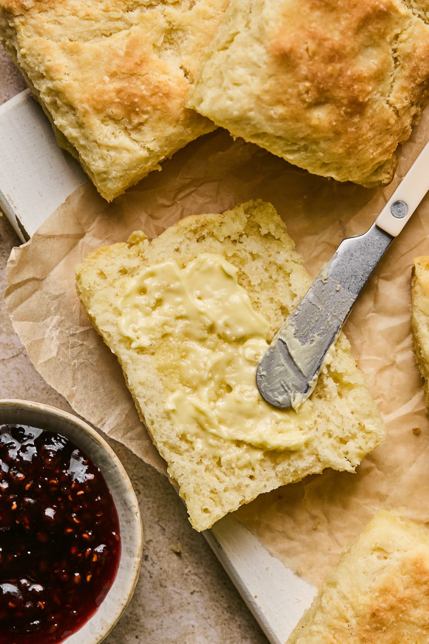 a butter knife spreading butter on a homemade buttermilk biscuit. 