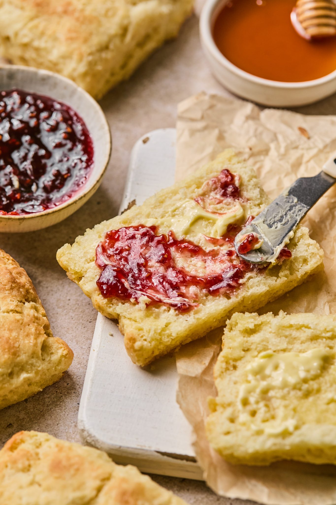 a knife spreading jam on a biscuit. 