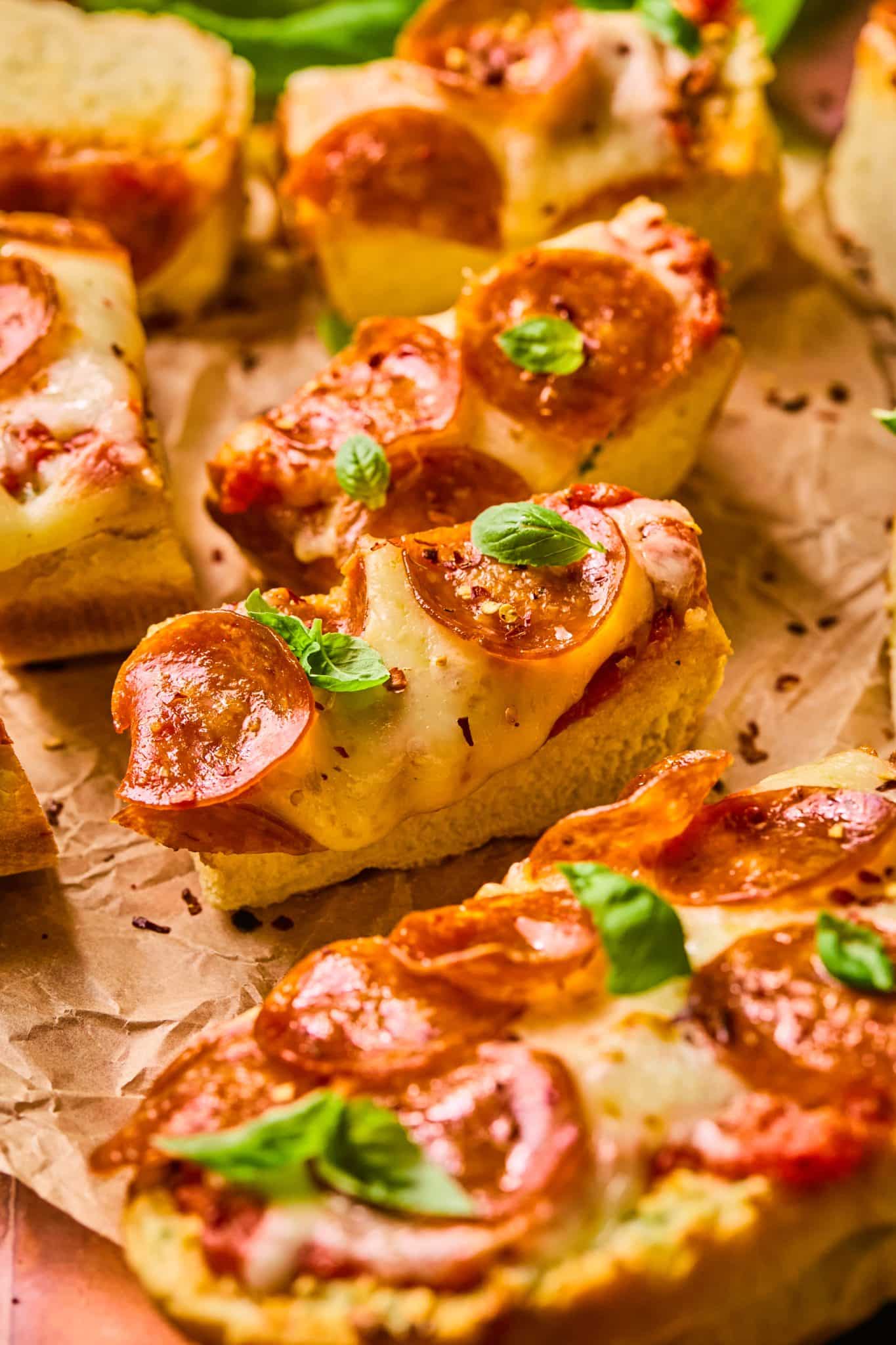 a slice of garlic bread pizza topped with fresh basil and chili flakes. 