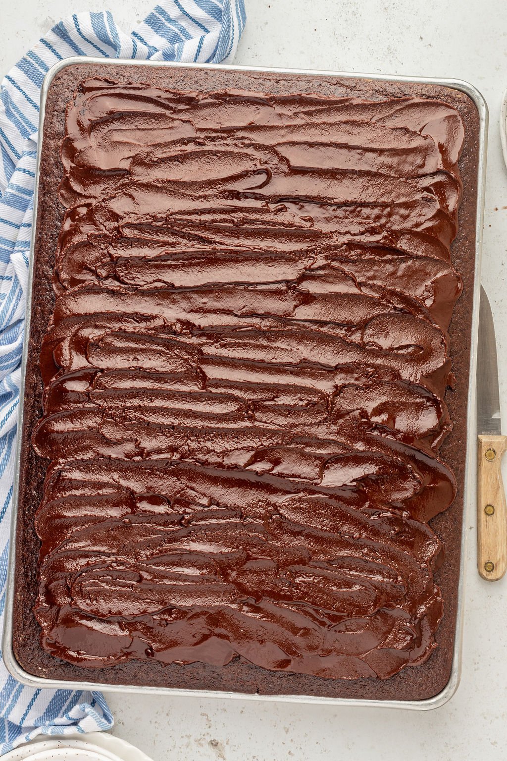 Half sheet pan with a chocolate cake and chocolate frosting.