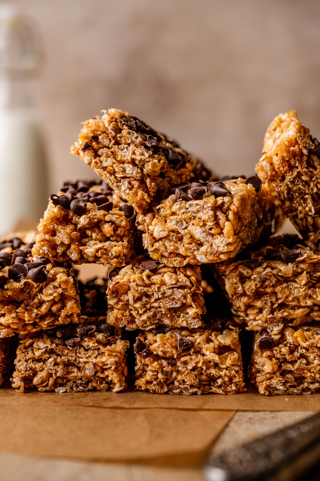 stacked granola bars on parchment paper with mini chocolate chips on top. 