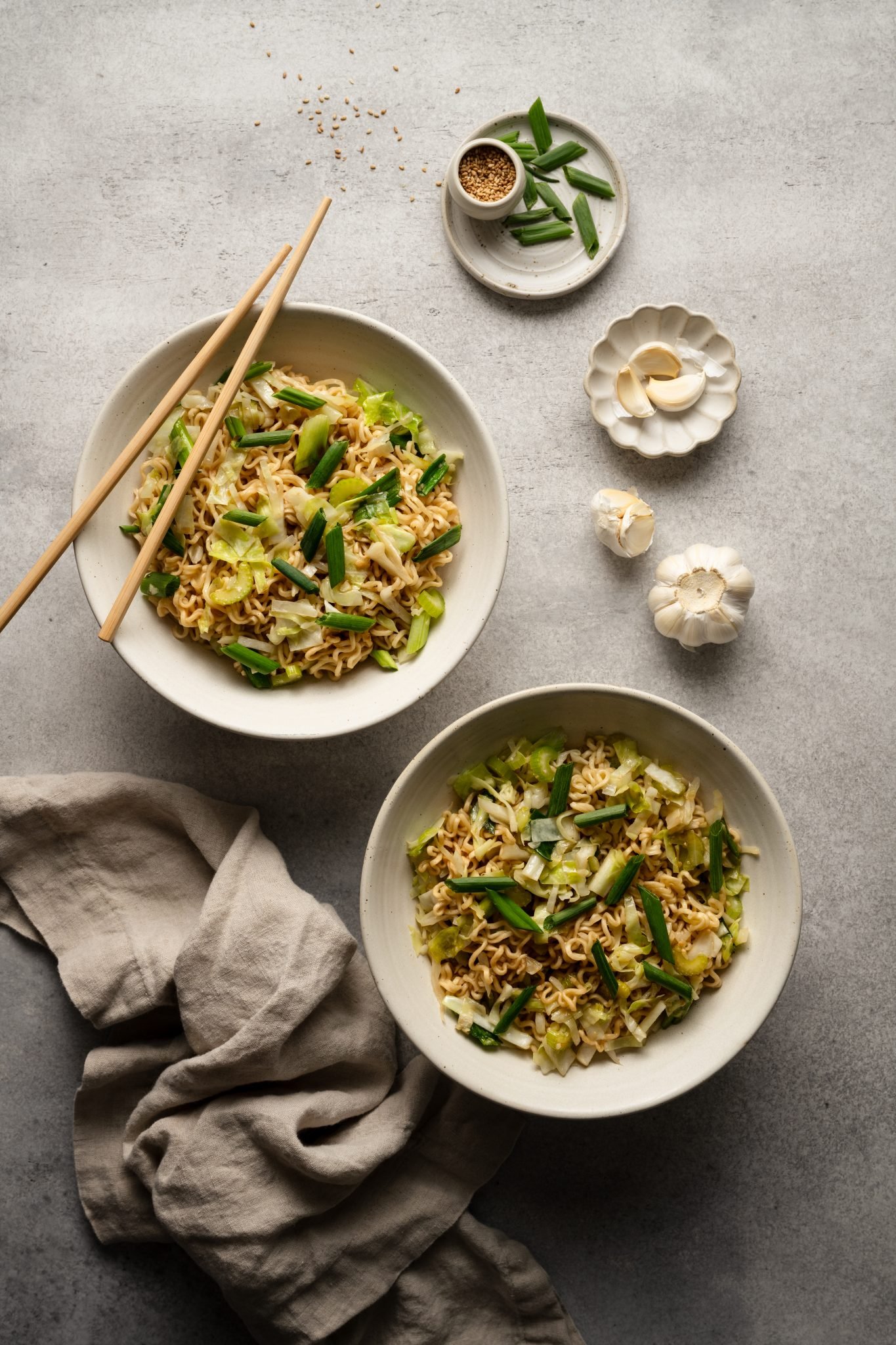 two white bowls filled with chow mein made with cabbage, celery, and green onions. 