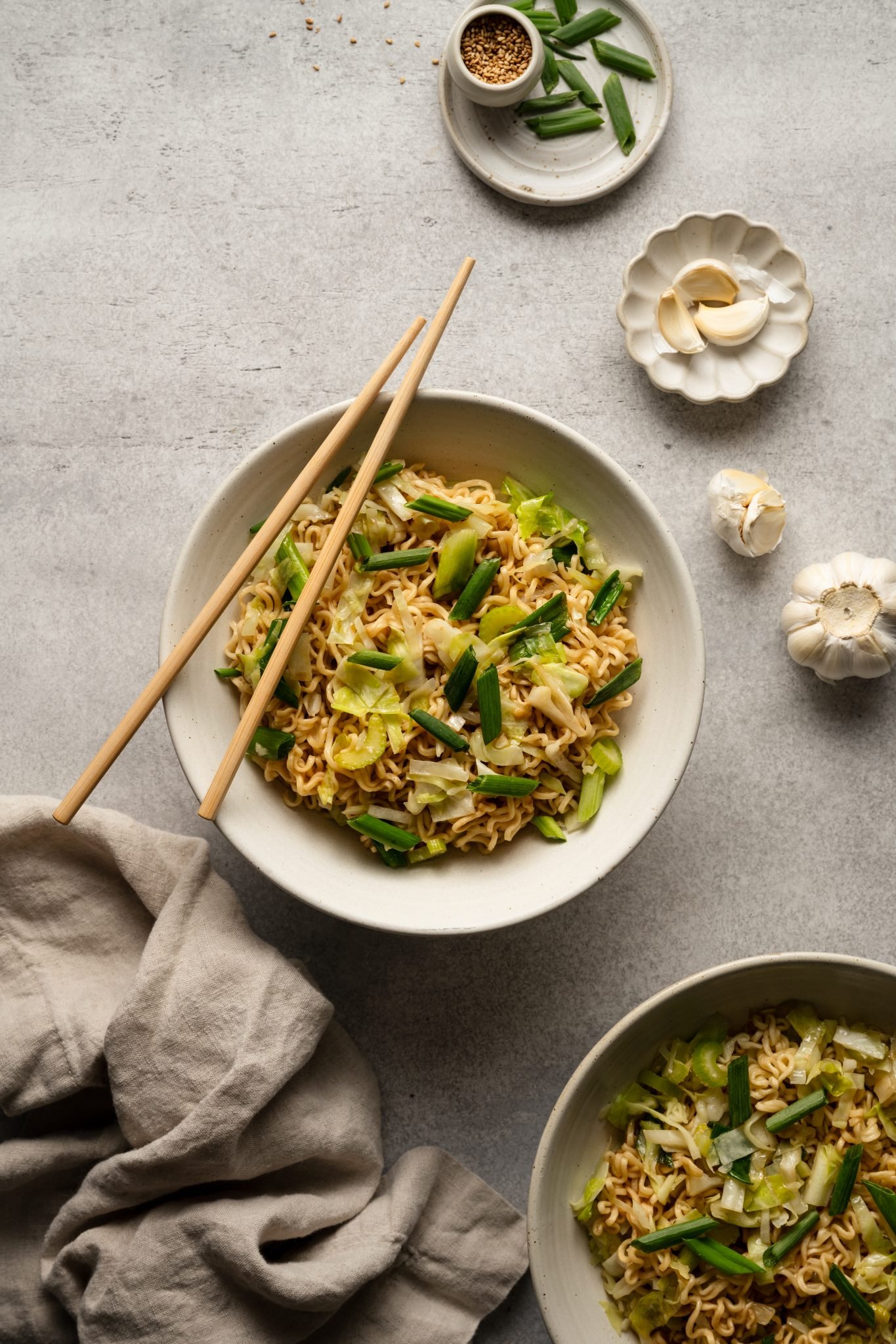 two white bowls filled with chow mein made with cabbage, celery, and green onions. 