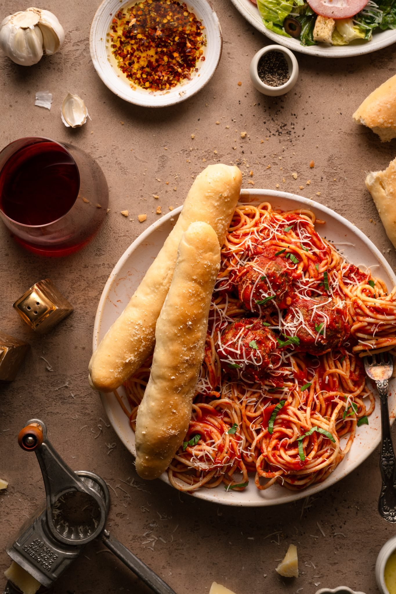 spaghetti and meatballs on a plate with breadsticks on the side. 