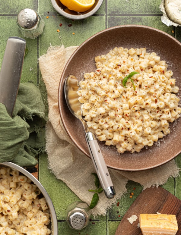 Creamy one pot boursin pasta in brown bowl with spoon on top of table scape.