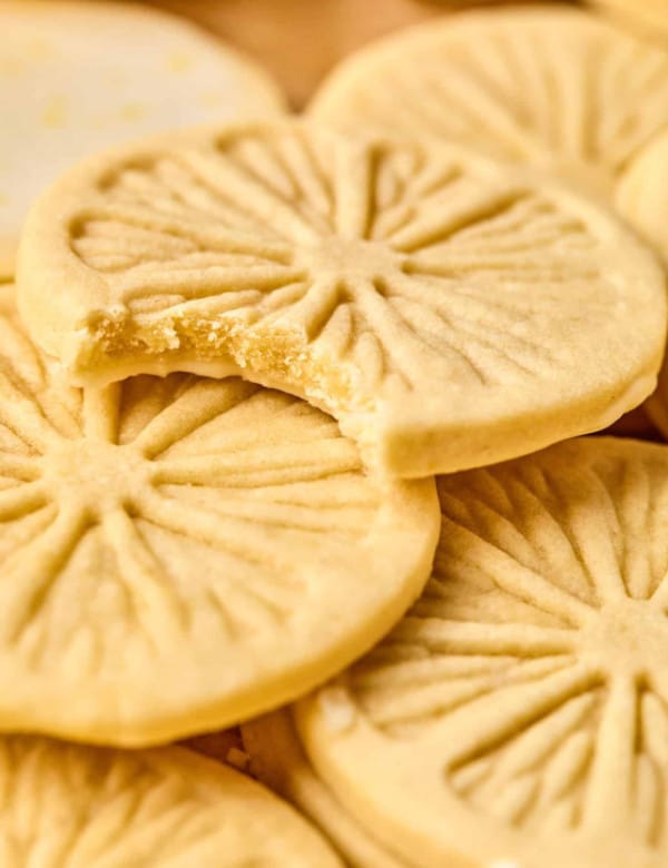 Lemonade cookies piled on top of each other and the top cookie has a bite taken out of it showing the inside of the cookie.