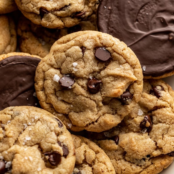 Plate of chocolate chip cookies dipped in chocolate with some of the cookies turned over so you can see the chocolate side.