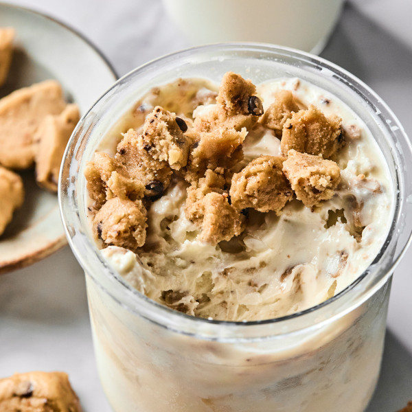 Ninja creami protein vanilla base recipe in ninja creami pint container topped with cookie dough pieces.