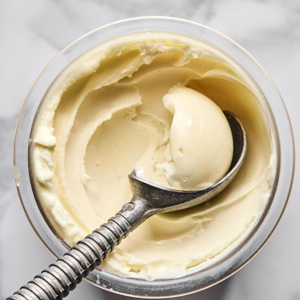 Ninja creami vanilla protein ice cream being scooped out with ice cream scoop out of pint container before adding mix-ins.