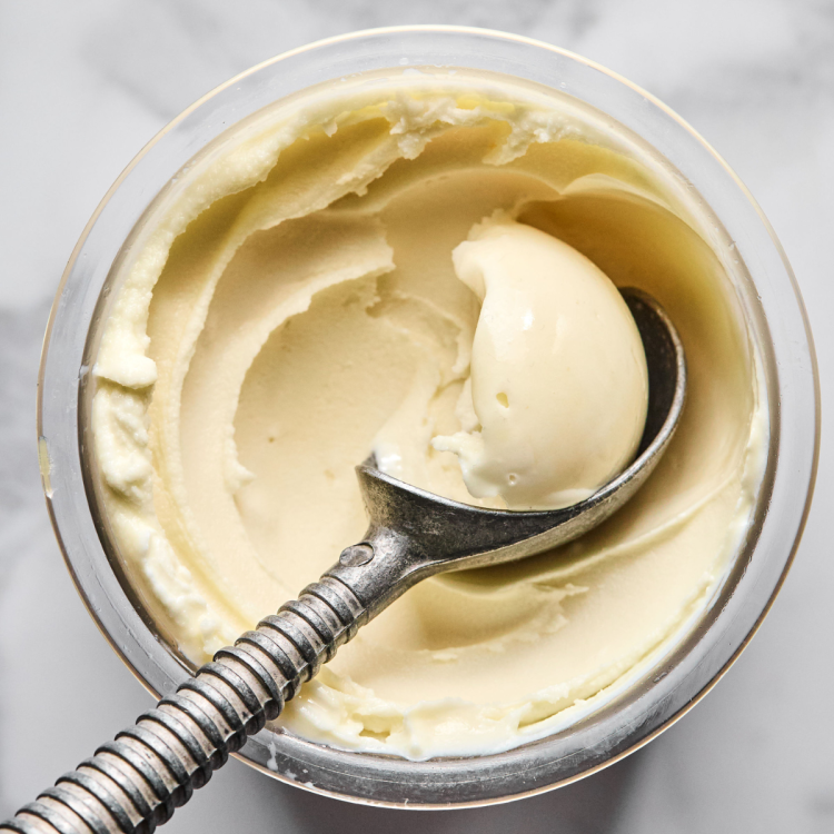 Ninja creami vanilla ice cream being scooped with ice cream scoop out of pint container.