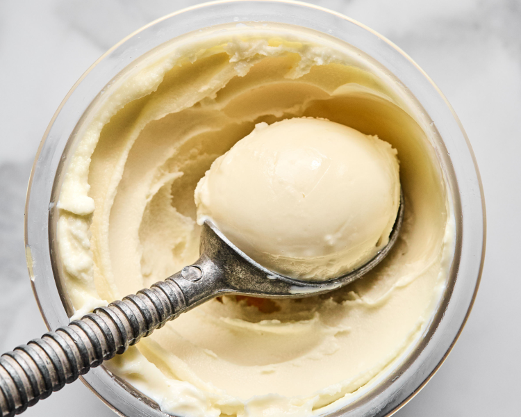 Ice cream scoop scooping out vanilla protein ice cream out of ninja creami pint container.
