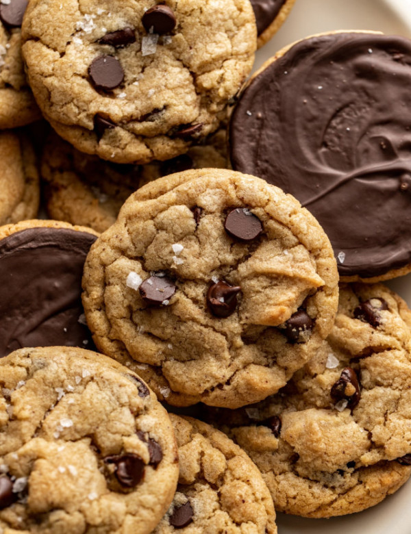 Plate of chocolate chip cookies dipped in chocolate with some of the cookies turned over so you can see the chocolate side.