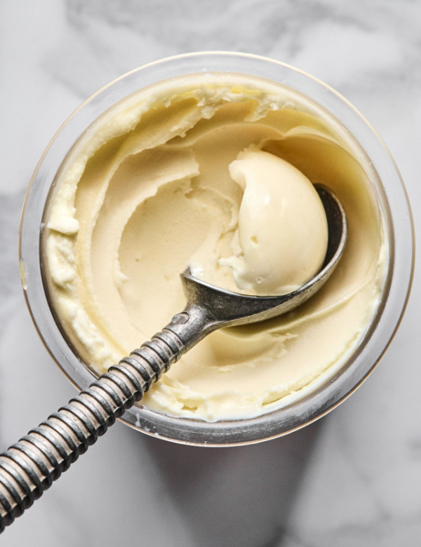 Ninja creami vanilla protein ice cream being scooped out with ice cream scoop out of pint container before adding mix-ins.