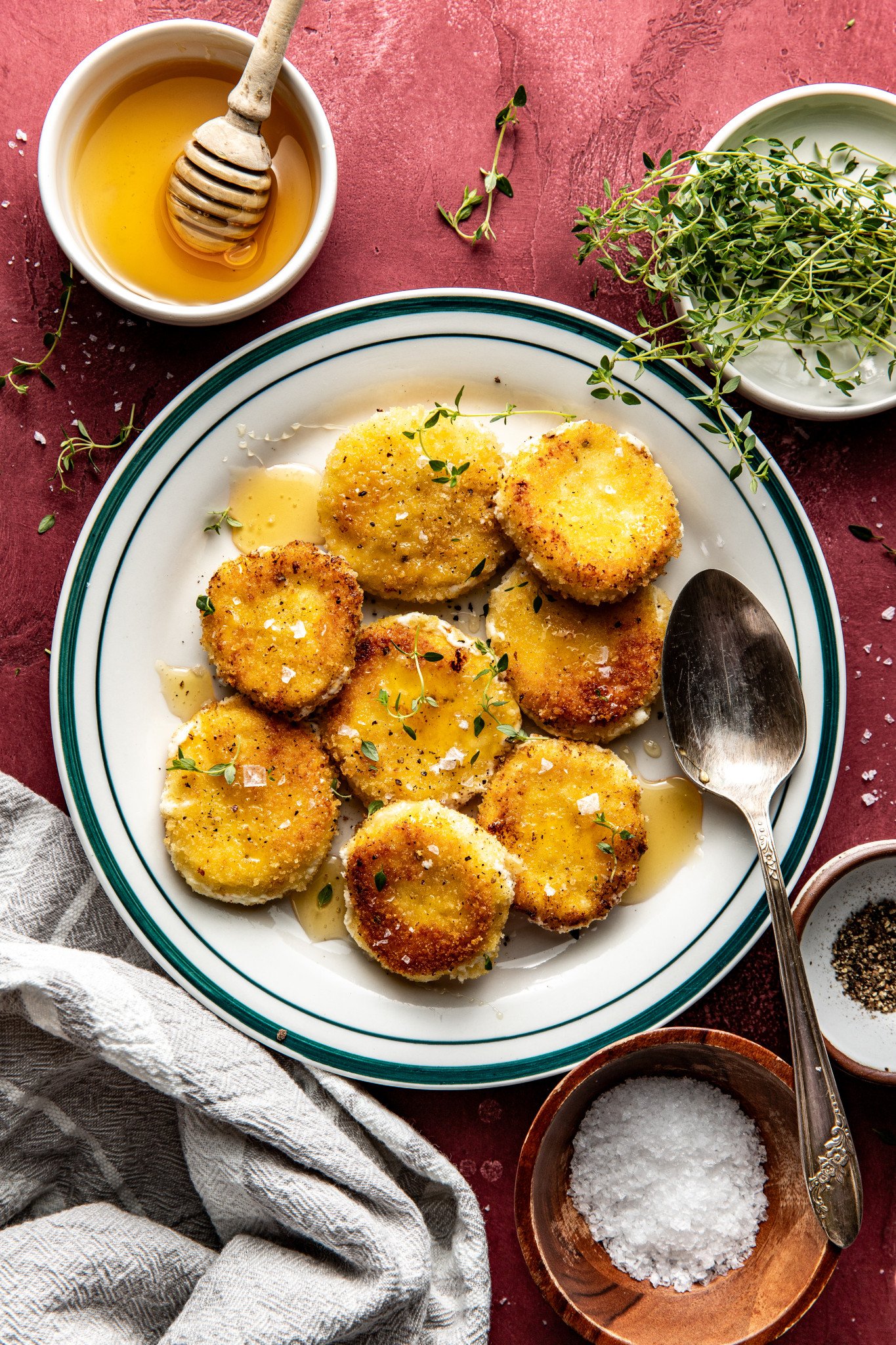 Fried goat cheese croutons on plate drizzled with honey and spoon on plate.