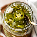 Pickled jalapeno in mason jar with fork.