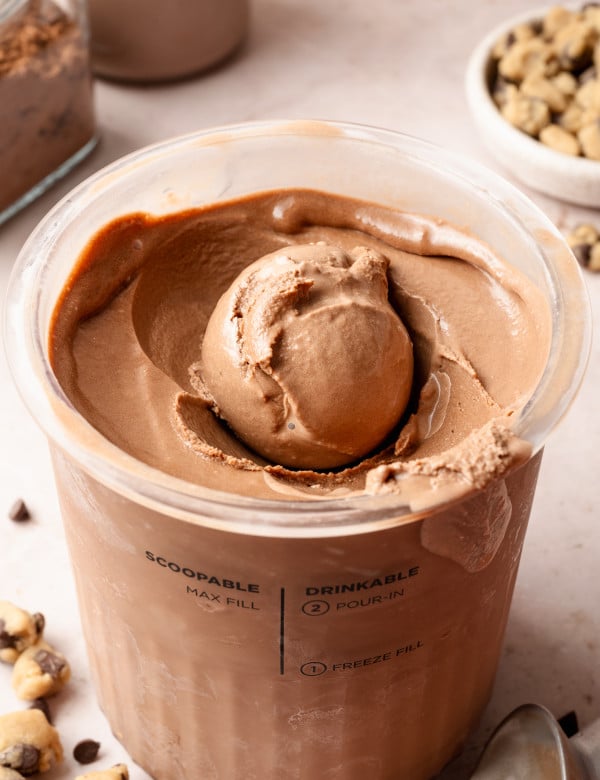 Chocolate ice cream scooped up in pint container.