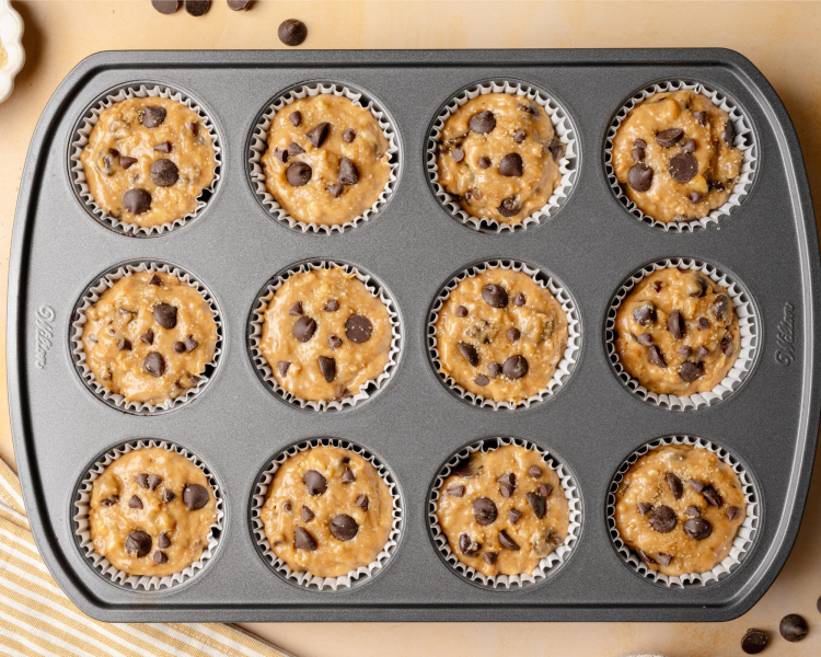 Muffin liners filled with banana chocolate chip batter before baking.