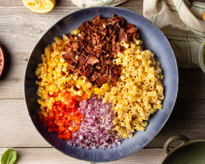 Pasta salad ingredients added to large blue bowl.