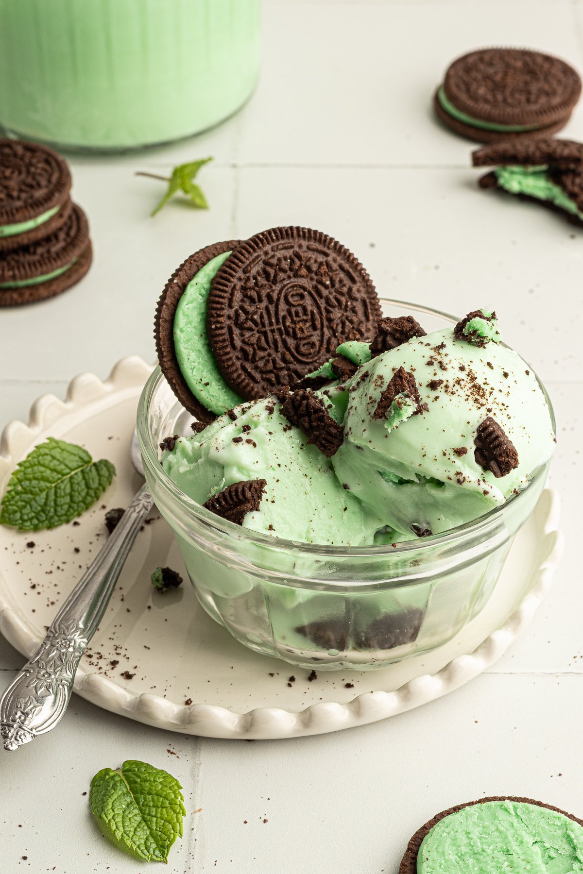 Glass dish filled with scoops of mint chocolate chip protein ice cream, topped with crushed mint sandwich cookies and whole cookies for garnish.