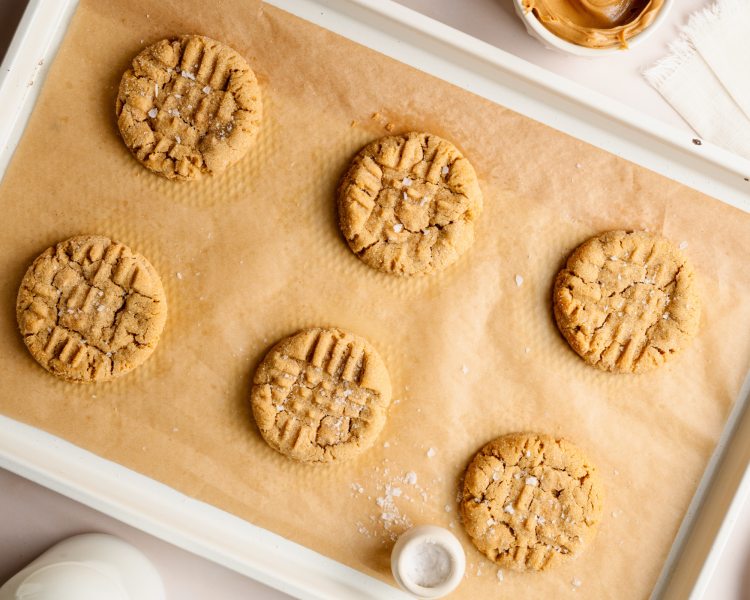 Baked peanut butter chip cookies sprinkled with flaky salt on parchment lined tray.