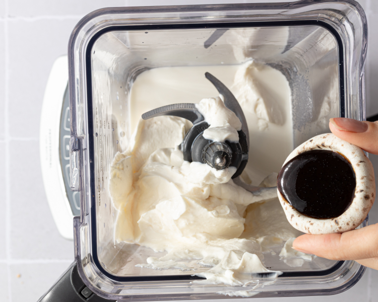 Pouring ingredients for ninja creami vanilla frozen yogurt into blender.