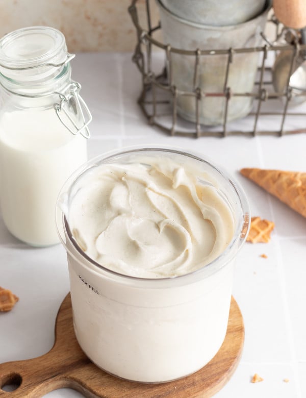 Ninja creami vanilla frozen yogurt in pint container on top of wooden board.