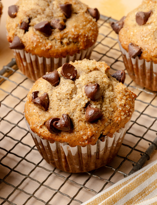 Upclose shot of 3 banana chocolate chip muffins cooling on wire rack.