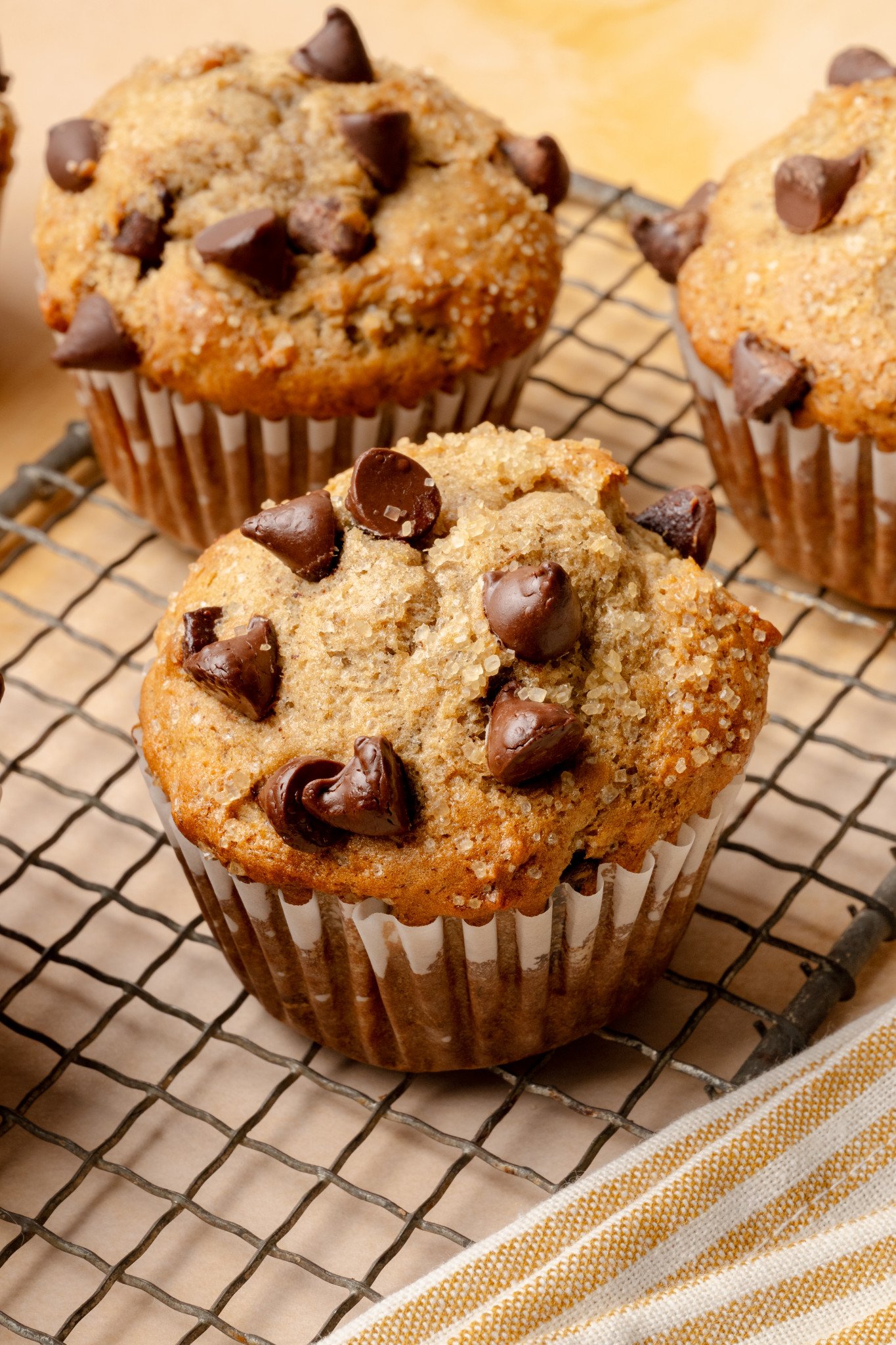 Upclose shot of 3 banana chocolate chip muffins cooling on wire rack.