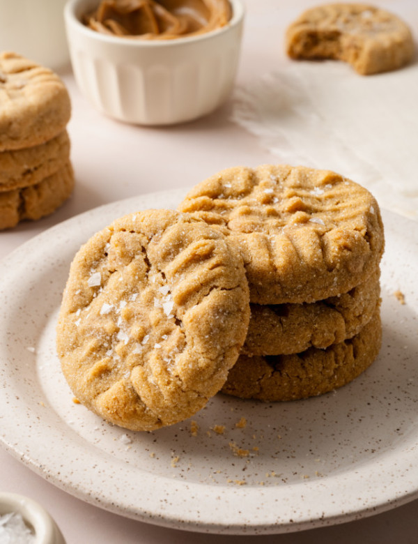 A stack of three peanut butter cookies on a plate with a fourth cookie stacked vertically against them.