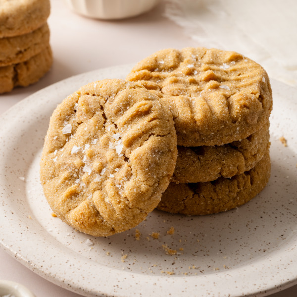 A stack of three peanut butter cookies on a plate with a fourth cookie stacked vertically against them.