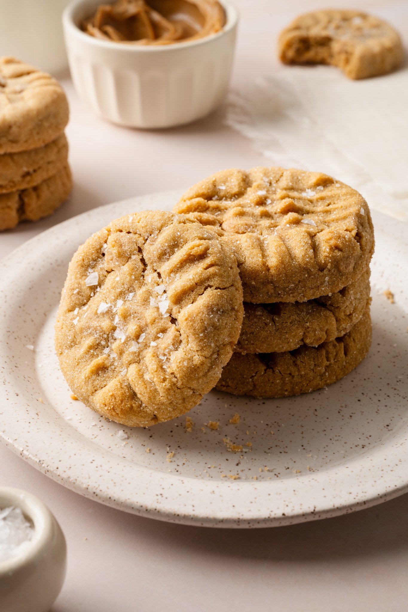 A stack of three peanut butter cookies on a plate with a fourth cookie stacked vertically against them.