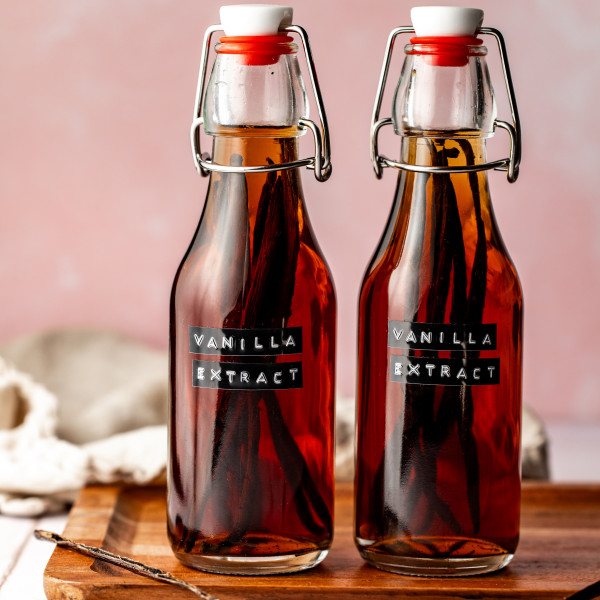 Homemade vanilla extract bottles on wood cutting board.