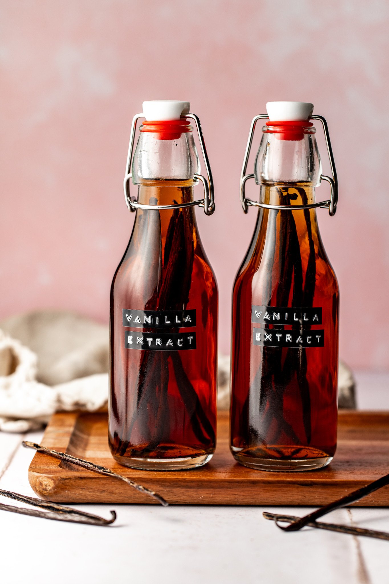Homemade vanilla extract bottles on wood cutting board.
