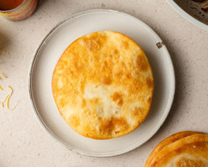 A second fried tortilla has been placed on top of the meat and bean layer, forming a sandwich-style stack on a plate.