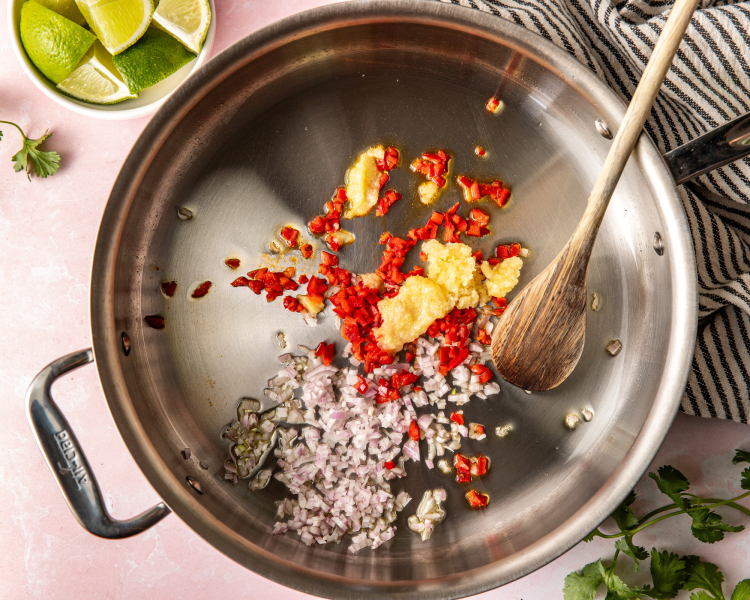 Ginger, garlic, shallot, olive oil and fresno chili add to hot skillet before adding in ground chicken.
