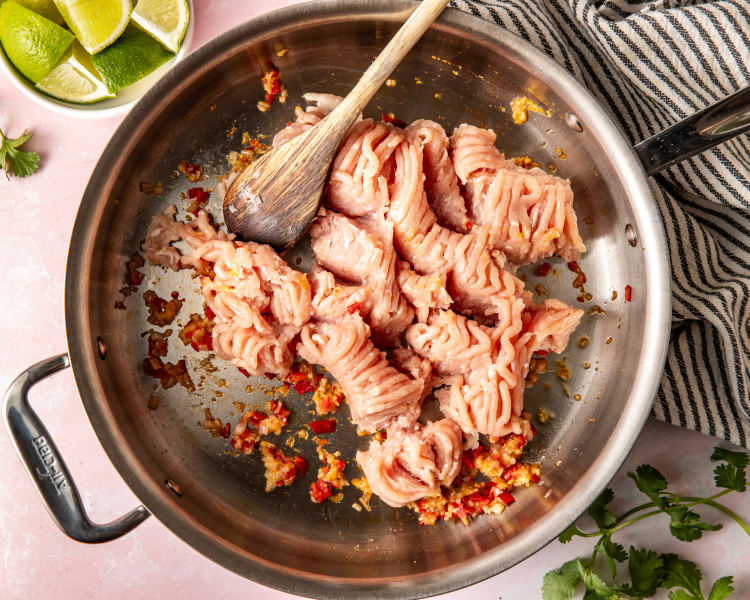 Raw ground chicken in large skillet.