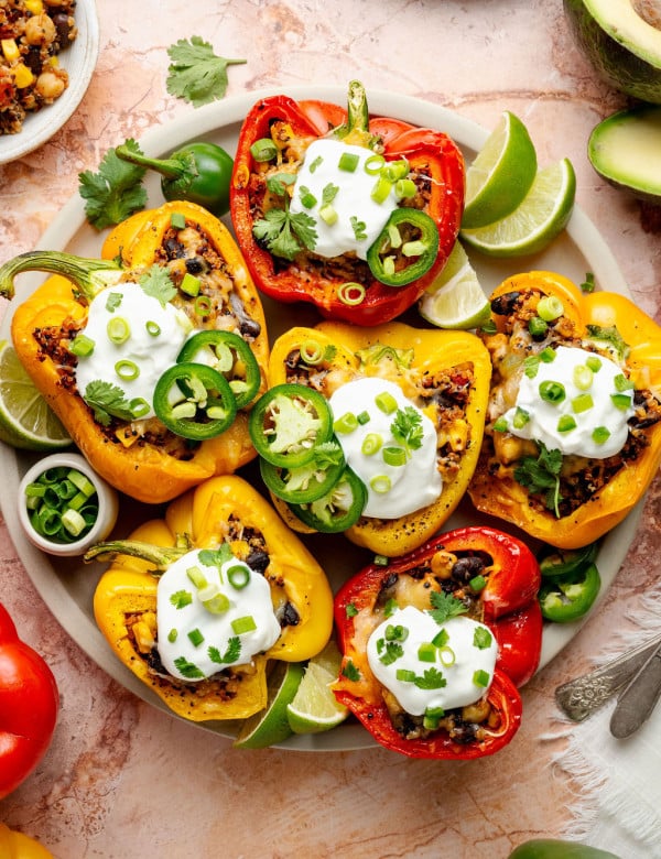 Colorful medley of cooked stuffed peppers in a baking dish with bubbly melted cheese and visible bits of corn and black beans.