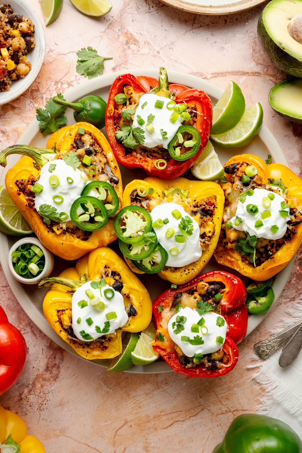 Colorful medley of cooked stuffed peppers in a baking dish with bubbly melted cheese and visible bits of corn and black beans.