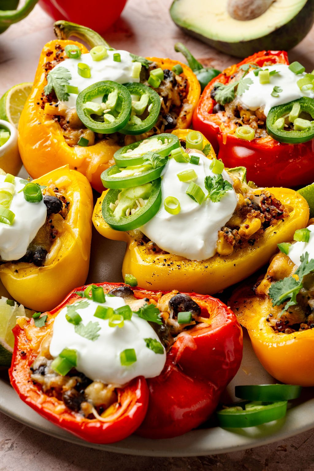 Close-up of a red bell pepper filled with hearty quinoa stuffing, with melted cheese and fresh green herbs on top.