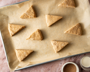 Unbaked scone dough cut into triangles on a parchment-lined baking tray.