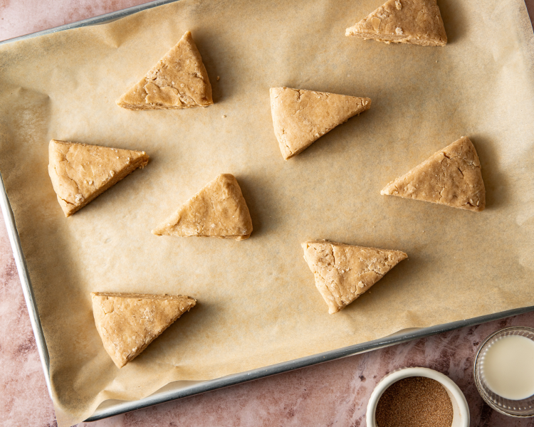 Unbaked scone dough cut into triangles on a parchment-lined baking tray.
