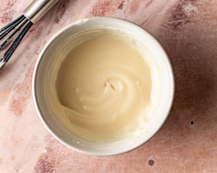 Icing ingredients mixed together in small white bowl.
