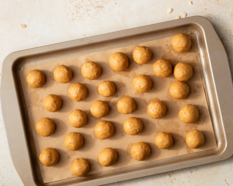 Peanut butter balls on a parchment-lined tray after chilling in the freezer for 30 minutes before dipping in chocolate.