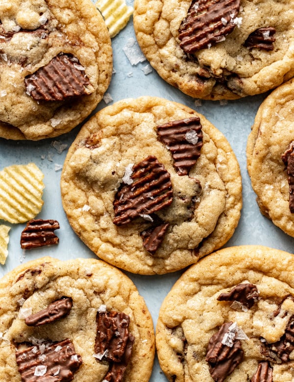 Baked chocolate potato chip cookies on table garnished with flaky sea salt.