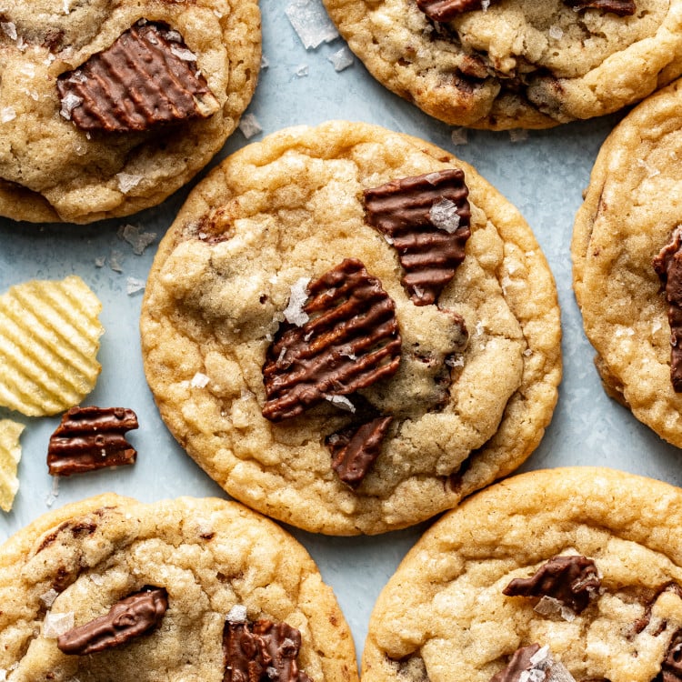 Baked chocolate potato chip cookies on table garnished with flaky sea salt.