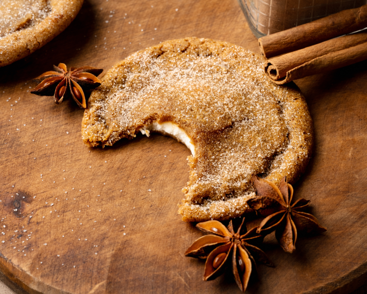 Upclose image of pumpkin cheesecake cookie with bite taken out of the center on wood cutting board.
