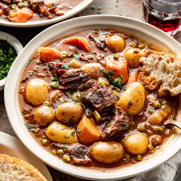 Beef stew in bowl with bread for dipping.