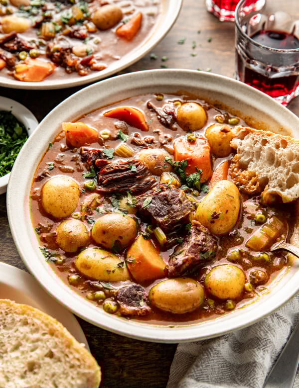 Beef stew in bowl with bread for dipping.