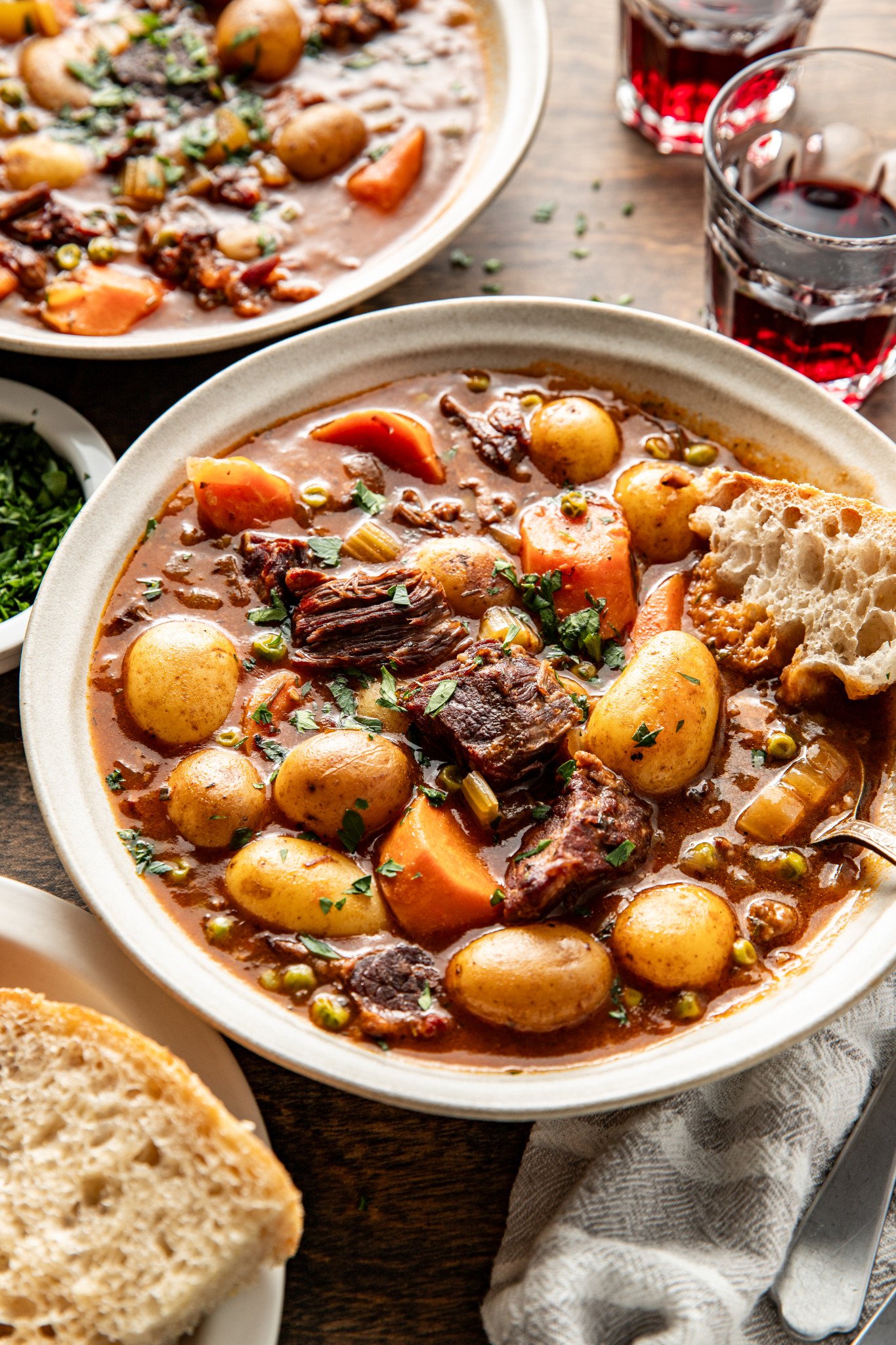 Beef stew in bowl with bread for dipping.
